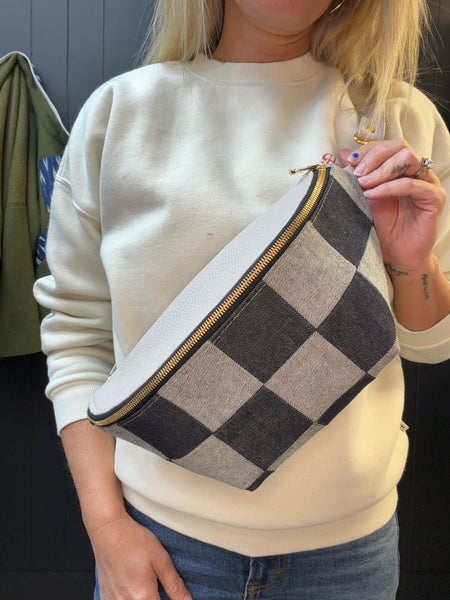Person holding a checkered bag with a neutral background