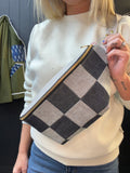 Person holding a checkered pouch with a neutral background