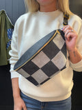 Person holding a checkered bag with a neutral background